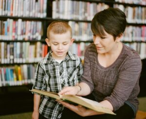 Vuxen läser en bok tillsammans med ett barn i ett bibliotek