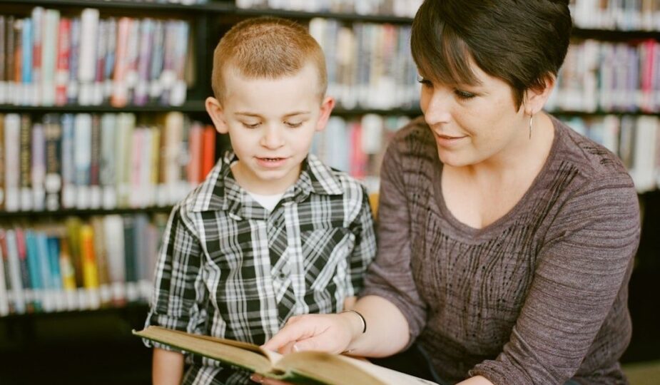 Vuxen läser en bok tillsammans med ett barn i ett bibliotek